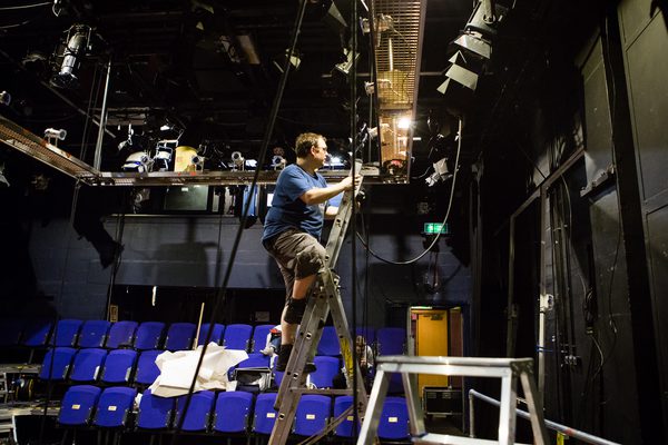 In our Traverse 2 performance space, a technician is up a ladder rigging lights.