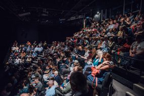 A sold-out crowd is seated in our larger performance space