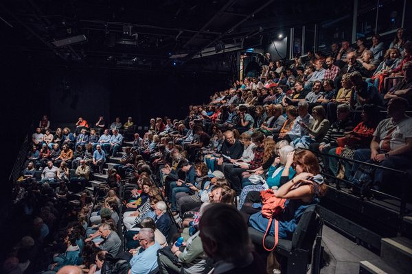 A sold-out crowd is seated in our larger performance space