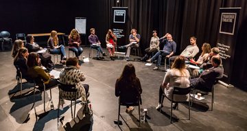 Workshop participants and leaders sit talking in a circle