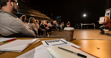 A workshop in our large Traverse 1 performance space. A note book is lying open on a table.