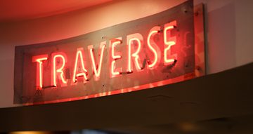 Neon sign reading 'TRAVERSE'.
