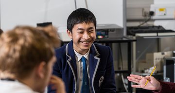 A teenage boy in a smart blue blazer smiles at the camera.