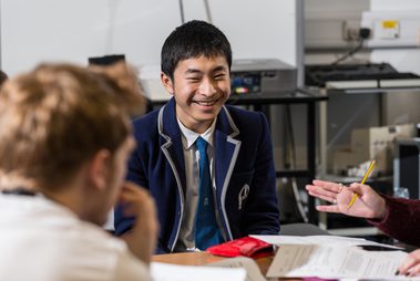 A teenage boy in a smart blue blazer smiles at the camera.